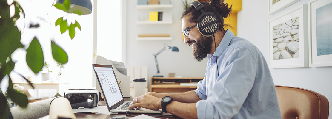 man with headphones sitting at laptop